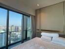 Modern bedroom with city view through large windows