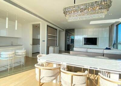 Spacious modern living and dining area with large windows, kitchen island, white furniture, and chandelier