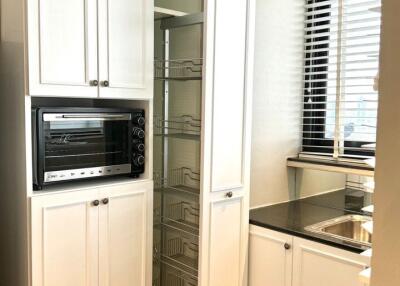 Modern kitchen with white cabinets, built-in oven, pull-out pantry storage, and a sink