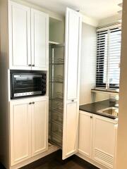 Modern kitchen with white cabinets, built-in oven, pull-out pantry storage, and a sink