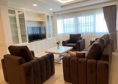 Spacious and well-lit living room with comfortable seating and a media center