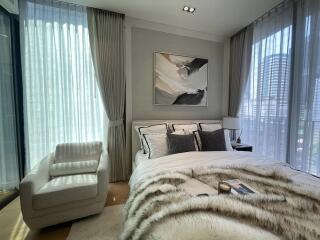 Modern bedroom with large windows, plush bedding, and elegant decor