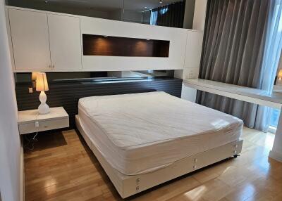 Modern bedroom with large bed, nightstand, and built-in storage