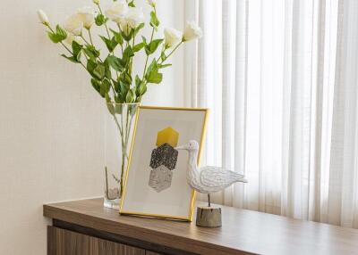 Decorative items on a wooden table with a vase of flowers and framed art