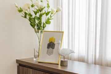 Decorative items on a wooden table with a vase of flowers and framed art