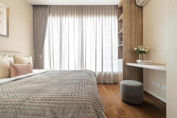 Modern bedroom with a large bed, grey bedding, and a study nook with a desk