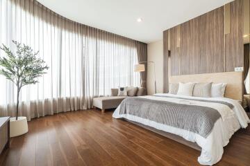 Well-lit bedroom with large window, bed, and seating area