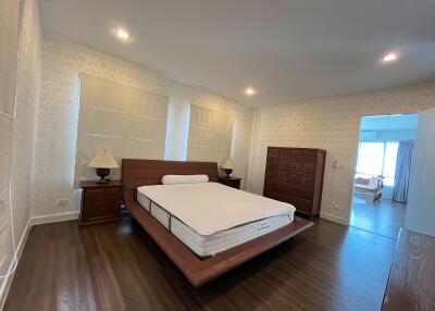 Spacious modern bedroom with a large bed and wooden furniture.
