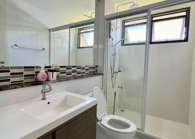 Modern bathroom with large mirror, sink, toilet, and glass-enclosed shower