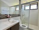 Modern bathroom with large mirror, sink, toilet, and glass-enclosed shower