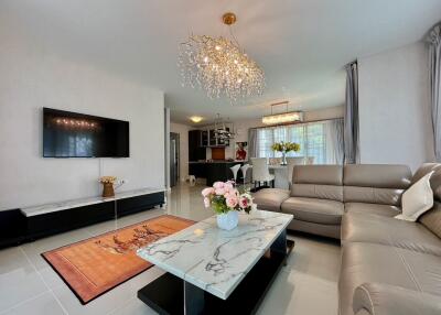 Modern living room with chandelier, TV, and leather seating