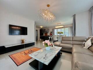 Modern living room with chandelier, TV, and leather seating