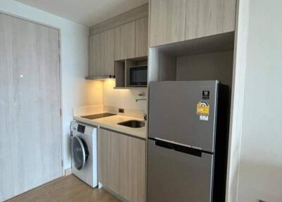 Modern kitchen with beige cabinets, stainless steel refrigerator, built-in microwave, and washing machine.