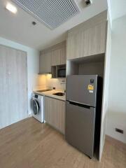 Modern kitchen with beige cabinets, stainless steel refrigerator, built-in microwave, and washing machine.