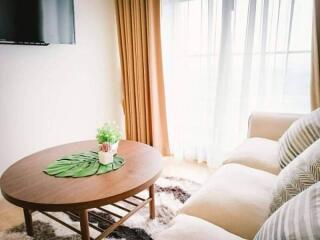 Cozy living room with a white sofa, wooden coffee table, and large window with curtains