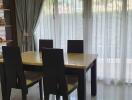 Dining area with table and chairs near large window with curtains