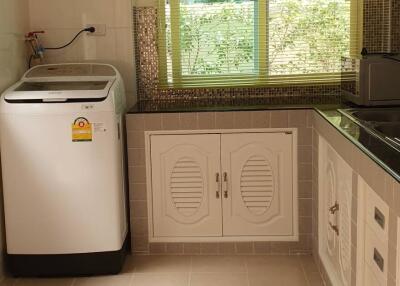 Well-lit laundry room with a washing machine and storage cabinets