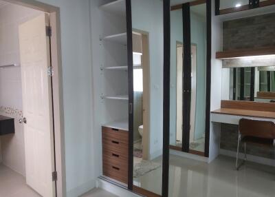 Modern bedroom with built-in shelves, mirrored sliding wardrobe, work desk, and en-suite bathroom