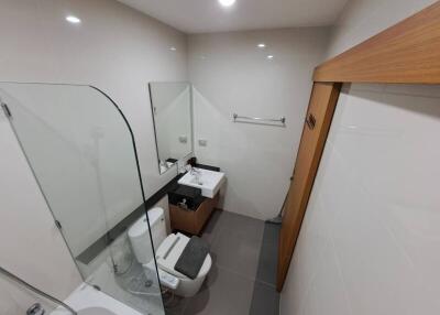 Modern bathroom with a bathtub, sink, toilet, and mirror