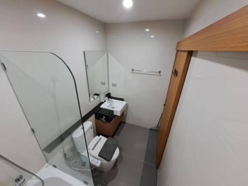 Modern bathroom with a bathtub, sink, toilet, and mirror