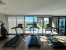 Modern gym with treadmills and elliptical in a well-lit room overlooking a courtyard