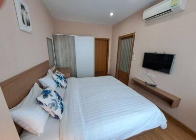 Modern bedroom with white linens and wall-mounted TV