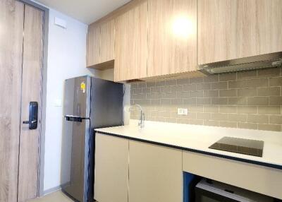 Modern kitchen with wooden cabinets, stainless steel refrigerator, microwave and stovetop