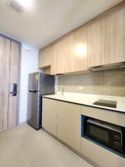 Modern kitchen with wooden cabinets, stainless steel refrigerator, microwave and stovetop