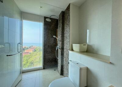 Modern bathroom with glass shower, toilet, and ocean view
