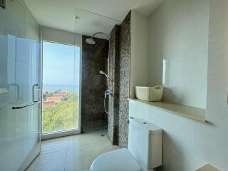 Modern bathroom with glass shower, toilet, and ocean view