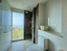 Modern bathroom with glass shower, toilet, and ocean view
