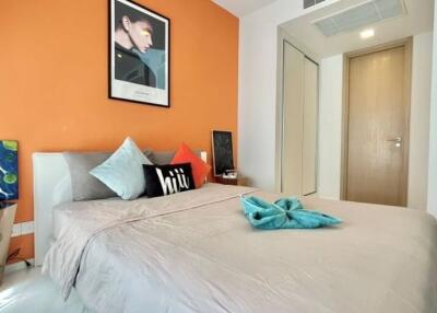 Modern bedroom with orange accent wall, grey bedding, and decorative pillows