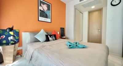 Modern bedroom with orange accent wall, grey bedding, and decorative pillows