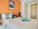 Modern bedroom with orange accent wall, grey bedding, and decorative pillows