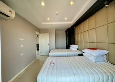 Modern bedroom with two beds, padded headboard wall, and recessed lighting