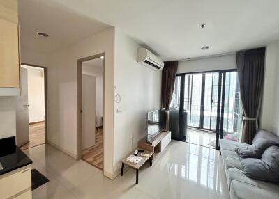 Modern living room with a sofa, TV, air conditioner, and balcony access