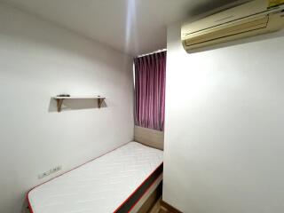 Small bedroom with a single bed, air conditioner, and shelf