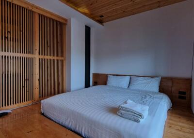 A cozy, modern bedroom with wooden elements, featuring a double bed and built-in closet