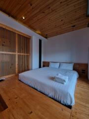 A cozy, modern bedroom with wooden elements, featuring a double bed and built-in closet