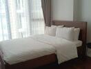 Well-lit bedroom with a wooden bed frame and white bedding