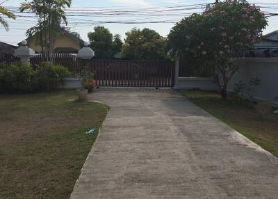 View of a driveway and front yard of a house with a gate