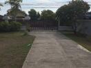 View of a driveway and front yard of a house with a gate