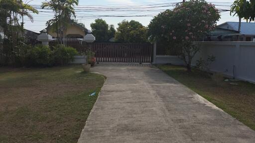 View of a driveway and front yard of a house with a gate