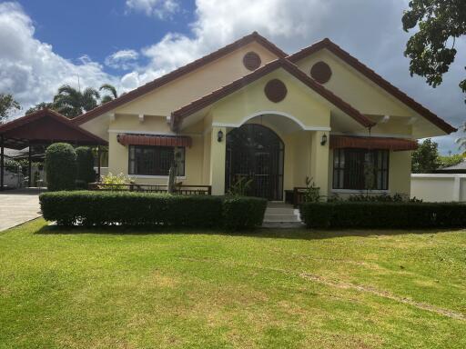 Exterior view of a single-story house with a red roof and well-maintained lawn