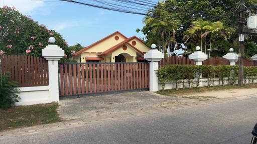 Exterior view of a house with red roof and wooden gate