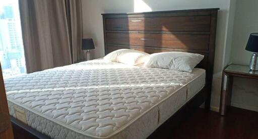 Bedroom with a large bed, dark wooden headboard, and nightstands with lamps