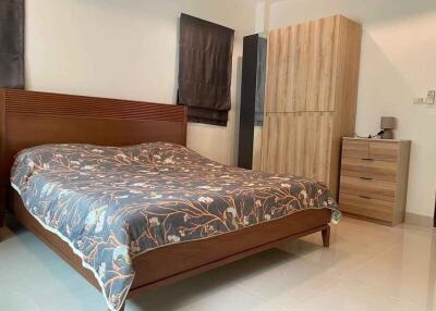 A modern bedroom with wooden furniture and a floral bedspread