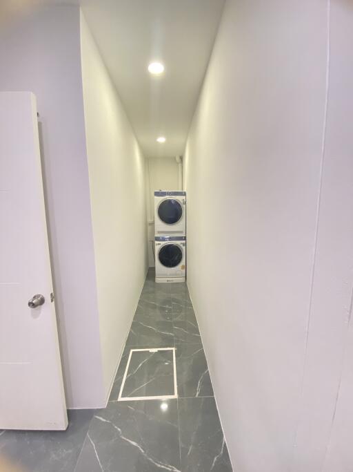 Narrow laundry room with modern stacked washer and dryer