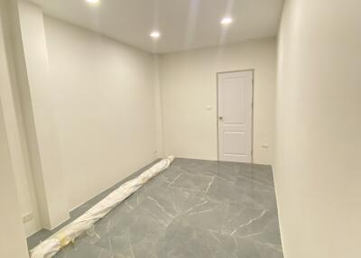 Empty room with white walls, grey tiled floor, and ceiling lights