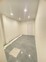 Empty room with white walls, grey tiled floor, and ceiling lights